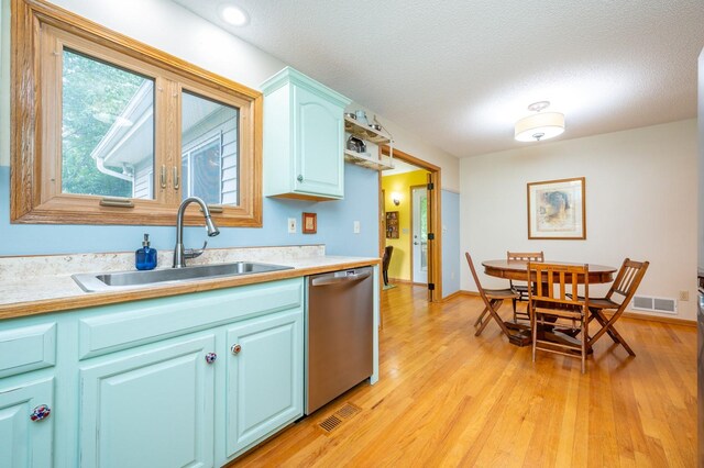 4774 Coachlight Dr, West Des Moines, IA 50265 - kitchen with stainless steel dishwasher, light wood-style floors, light countertops, a sink, and a textured ceiling