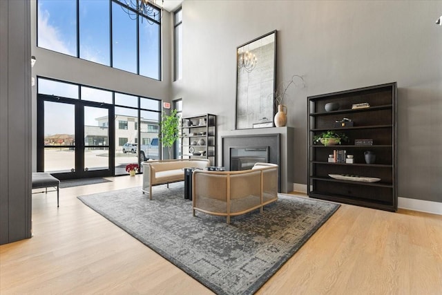 1645 SW Magazine Rd Unit 102, Ankeny, IA 50023 - living room featuring a glass covered fireplace, wood finished floors, a high ceiling, plenty of natural light, and a chandelier