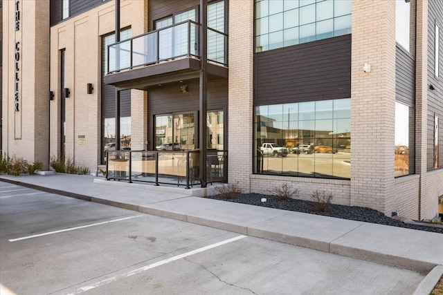 1645 SW Magazine Rd Unit 102, Ankeny, IA 50023 - view of exterior entry with a balcony, uncovered parking, and brick siding