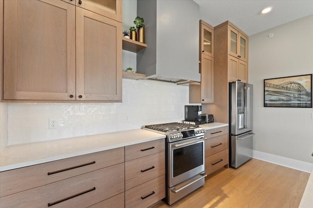 1645 SW Magazine Rd Unit 102, Ankeny, IA 50023 - kitchen featuring appliances with stainless steel finishes, wall chimney range hood, light wood-style floors, tasteful backsplash, and light countertops