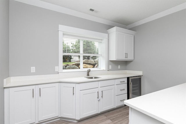 16206 Brookview Dr, Urbandale, IA 50323 - kitchen with wine cooler, a sink, light wood-type flooring, white cabinetry, and light countertops