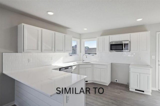 kitchen with white cabinetry, a sink, stainless steel appliances, and a peninsula