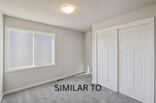 unfurnished bedroom with a closet, a textured ceiling, baseboards, visible vents, and carpet