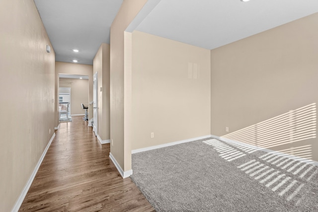 hall featuring baseboards, wood finished floors, and recessed lighting