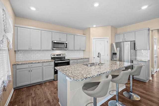 kitchen with appliances with stainless steel finishes, a sink, dark wood-style flooring, tasteful backsplash, and recessed lighting