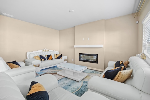 living area with a glass covered fireplace and baseboards