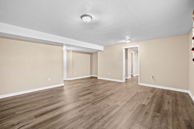 finished below grade area featuring a textured ceiling, wood finished floors, and baseboards