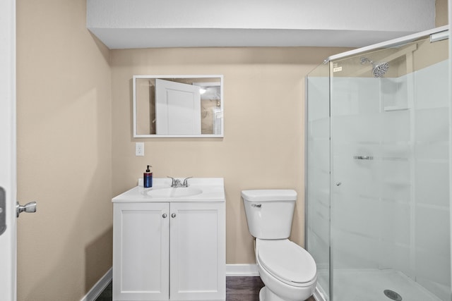 full bathroom featuring a stall shower, baseboards, vanity, and toilet