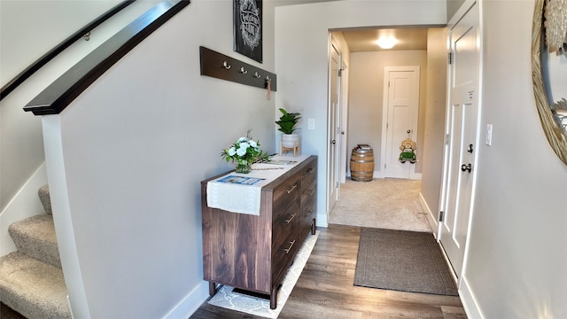 hall featuring baseboards, wood finished floors, and stairway