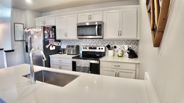 kitchen featuring appliances with stainless steel finishes, a sink, decorative backsplash, white cabinetry, and recessed lighting