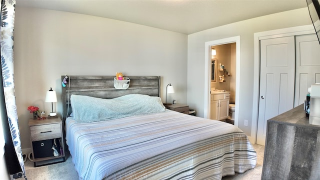 carpeted bedroom with ensuite bathroom and a closet