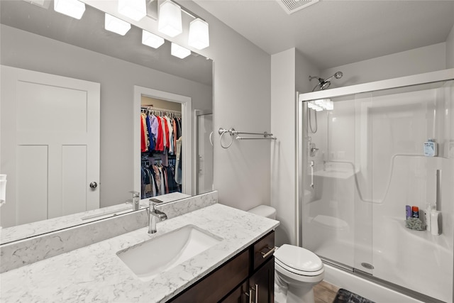 17127 Blue Sage Ln, Urbandale, IA 50323 - bathroom featuring a stall shower, toilet, vanity, and a spacious closet
