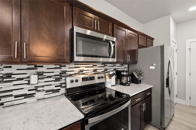 17127 Blue Sage Ln, Urbandale, IA 50323 - kitchen featuring appliances with stainless steel finishes, backsplash, dark brown cabinets, light stone countertops, and light wood finished floors