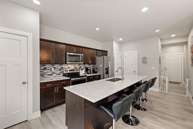 17127 Blue Sage Ln, Urbandale, IA 50323 - kitchen featuring appliances with stainless steel finishes, a sink, a breakfast bar, a center island with sink, and dark brown cabinets