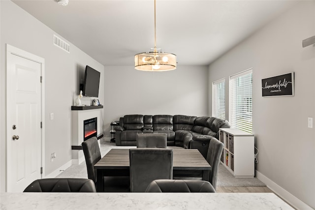 17127 Blue Sage Ln, Urbandale, IA 50323 - dining space with a glass covered fireplace, a chandelier, and baseboards
