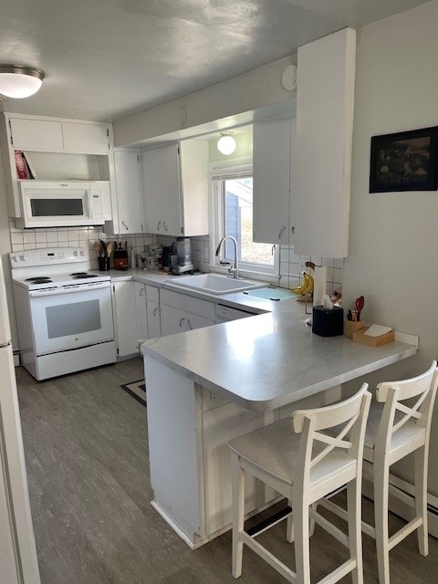 320 1st Ave, Grinnell, IA 50112 - kitchen featuring white appliances, tasteful backsplash, a peninsula, wood finished floors, and light countertops