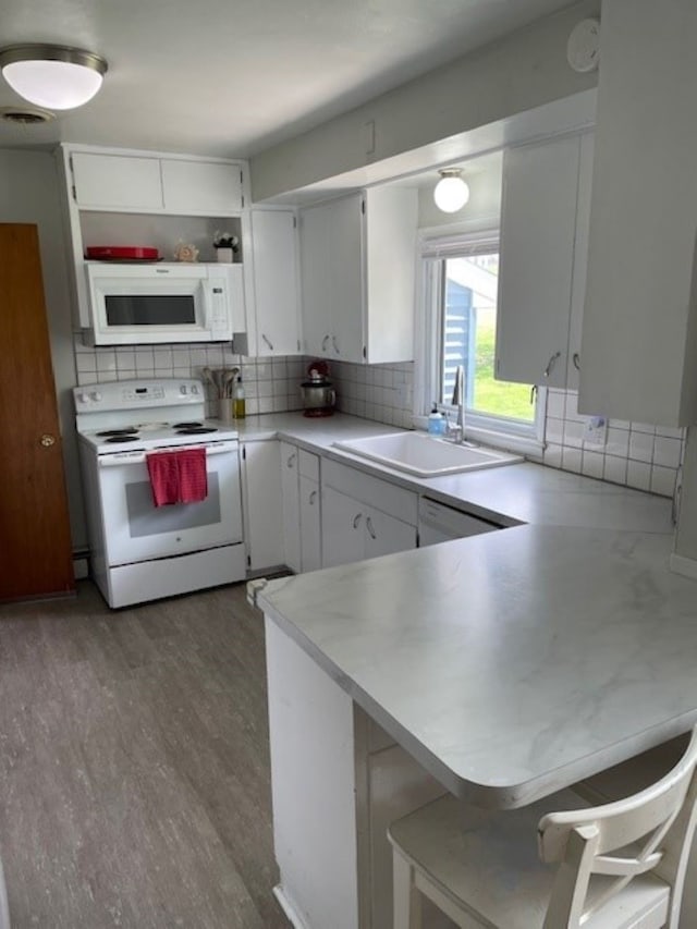 320 1st Ave, Grinnell, IA 50112 - kitchen featuring white appliances, decorative backsplash, a peninsula, and white cabinetry