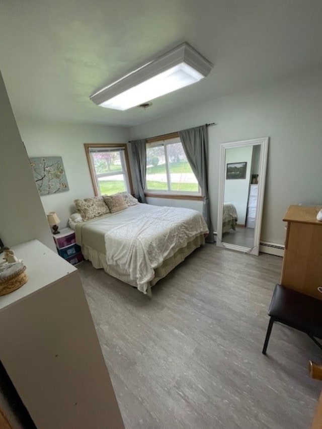 320 1st Ave, Grinnell, IA 50112 - bedroom featuring wood finished floors and a baseboard heating unit