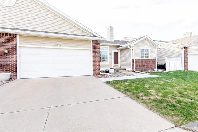single story home with driveway, a front yard, a chimney, an attached garage, and brick siding