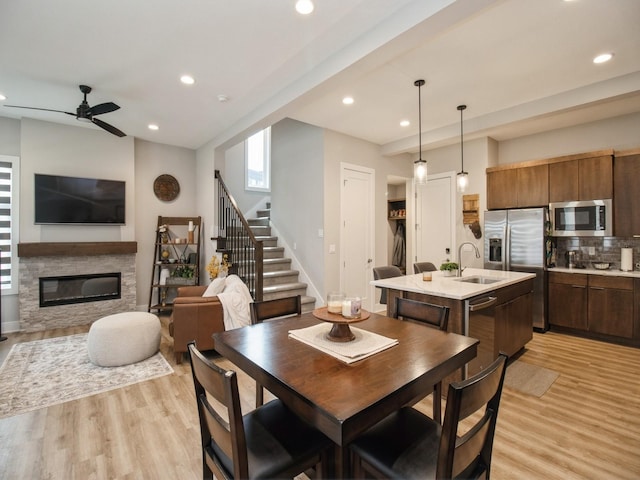 804 E 2nd St, Des Moines, IA 50309 - dining area featuring light wood-style flooring, stairs, ceiling fan, recessed lighting, and a stone fireplace