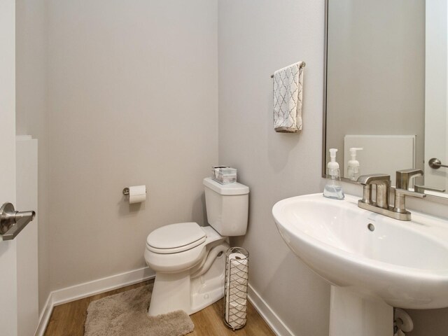 804 E 2nd St, Des Moines, IA 50309 - half bathroom with toilet, a sink, baseboards, and wood finished floors
