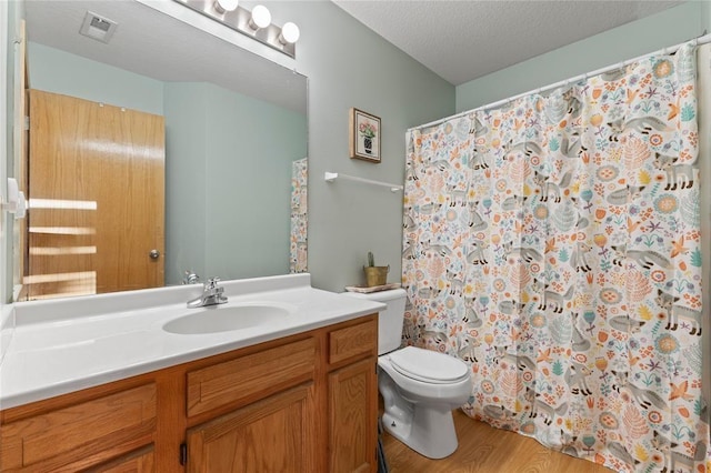 400 Coral Ridge Blvd, Pleasant Hill, IA 50327 - full bathroom with vanity, toilet, a textured ceiling, visible vents, and wood finished floors