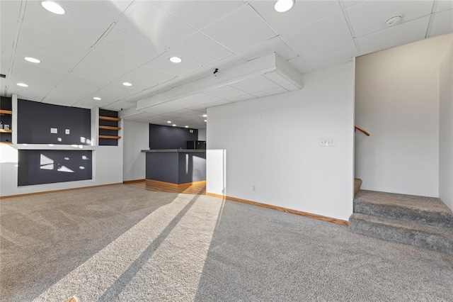 400 Coral Ridge Blvd, Pleasant Hill, IA 50327 - unfurnished living room featuring carpet, baseboards, stairs, bar, and a drop ceiling