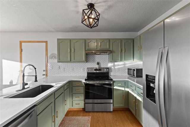 400 Coral Ridge Blvd, Pleasant Hill, IA 50327 - kitchen with green cabinets, under cabinet range hood, a sink, and appliances with stainless steel finishes