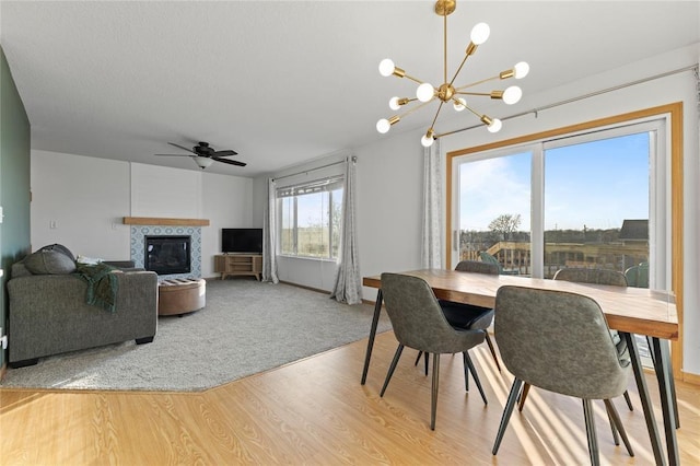 400 Coral Ridge Blvd, Pleasant Hill, IA 50327 - dining space with baseboards, a tiled fireplace, light wood-style floors, and ceiling fan with notable chandelier
