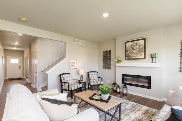 14521 Ironwood Ct, Urbandale, IA 50111 - living area featuring dark wood-type flooring, a glass covered fireplace, visible vents, recessed lighting, and baseboards
