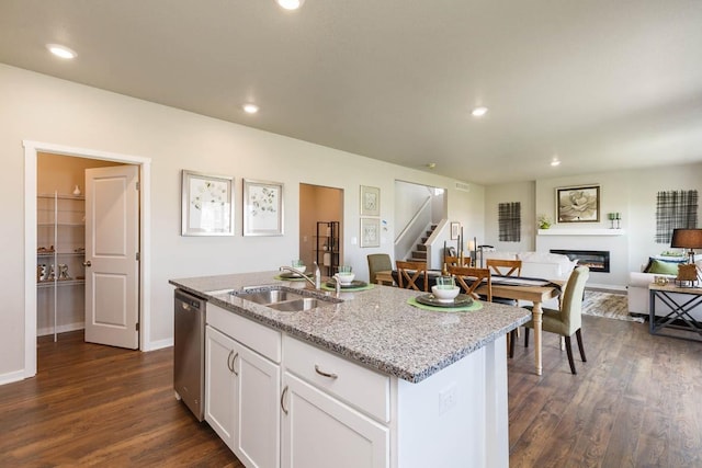 14521 Ironwood Ct, Urbandale, IA 50111 - kitchen featuring a glass covered fireplace, light stone countertops, dark wood-type flooring, stainless steel dishwasher, and a sink