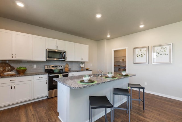 14521 Ironwood Ct, Urbandale, IA 50111 - kitchen featuring dark wood finished floors, a kitchen bar, white cabinets, appliances with stainless steel finishes, and a sink