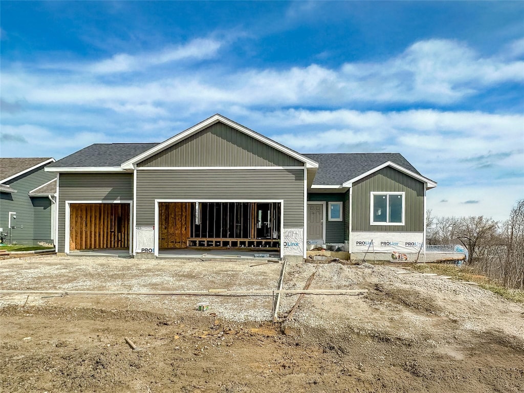 back of house with an attached garage, a shingled roof, and board and batten siding