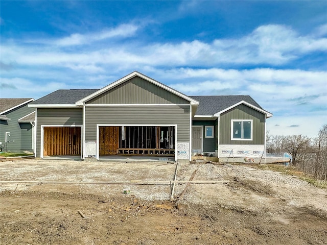 back of house with an attached garage, a shingled roof, and board and batten siding