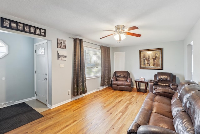 living area with light wood-style floors, visible vents, a ceiling fan, and baseboards