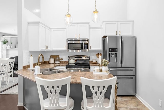 2403 NE Oak Dr Unit 6, Ankeny, IA 50021 - kitchen with a peninsula, white cabinetry, appliances with stainless steel finishes, a sink, and decorative backsplash