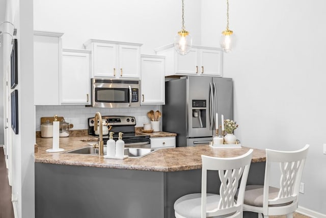 2403 NE Oak Dr Unit 6, Ankeny, IA 50021 - kitchen featuring a peninsula, white cabinetry, backsplash, stainless steel appliances, and a sink