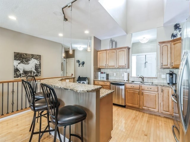 1417 NW 141st St Unit 17, Clive, IA 50325 - kitchen with light stone countertops, a kitchen island, a sink, stainless steel appliances, and a breakfast bar area