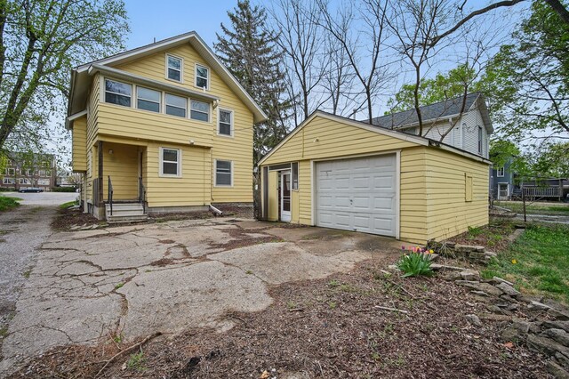 back of property with an outdoor structure, a garage, and aphalt driveway