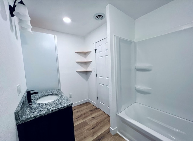 1402 E Marion St, Knoxville, IA 50138 - full bath with vanity, recessed lighting, shower / bath combination, visible vents, and wood finished floors