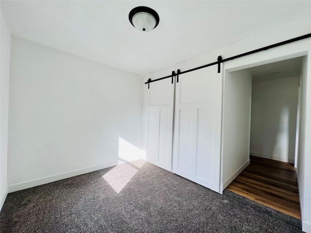 1402 E Marion St, Knoxville, IA 50138 - unfurnished bedroom featuring carpet floors, baseboards, and a barn door
