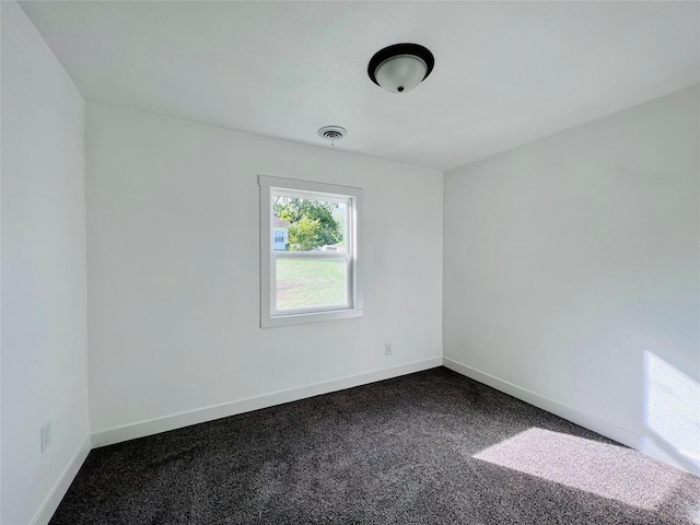 1402 E Marion St, Knoxville, IA 50138 - spare room featuring baseboards, dark colored carpet, and visible vents