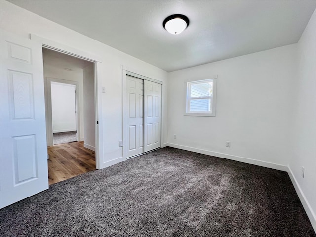 1402 E Marion St, Knoxville, IA 50138 - unfurnished bedroom featuring a closet, baseboards, and dark colored carpet