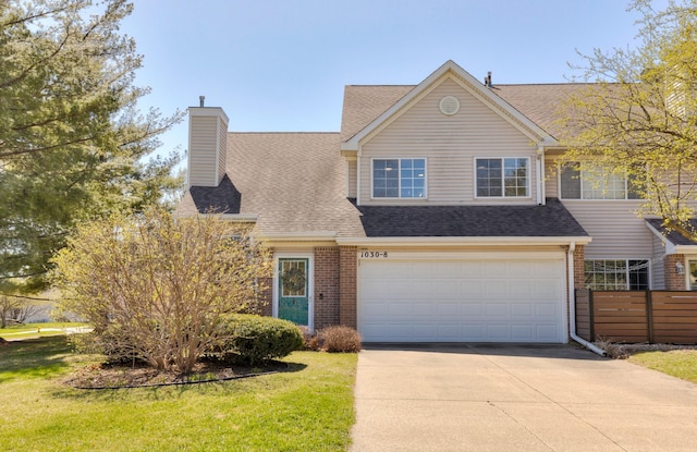 view of front facade with brick siding, a front yard, a shingled roof, and driveway