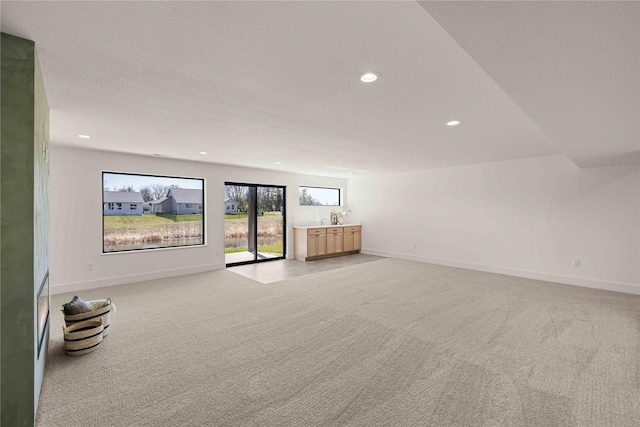 unfurnished living room with light carpet, recessed lighting, and baseboards