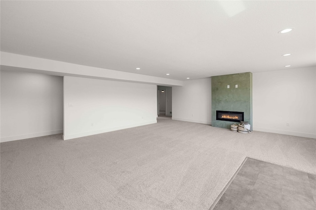 below grade area featuring baseboards, recessed lighting, light colored carpet, and a fireplace