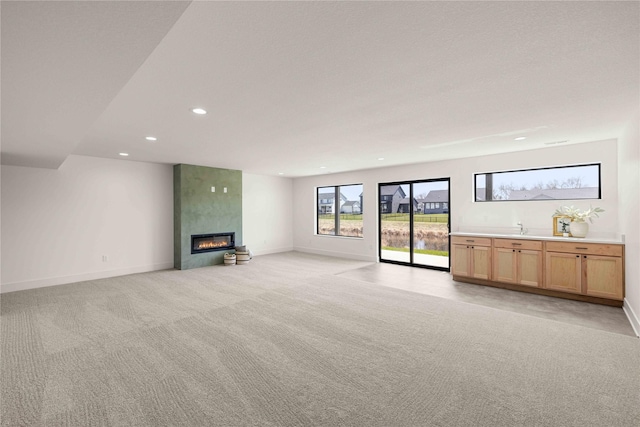 unfurnished living room with recessed lighting, a fireplace, light colored carpet, and baseboards