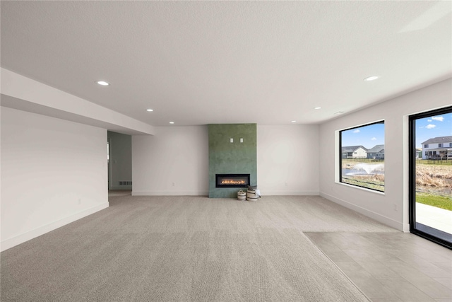 unfurnished living room with light carpet, recessed lighting, a large fireplace, and baseboards