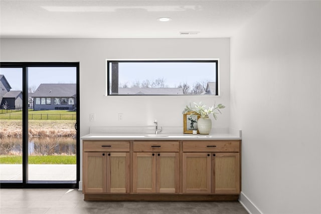 bar featuring visible vents, baseboards, and a sink