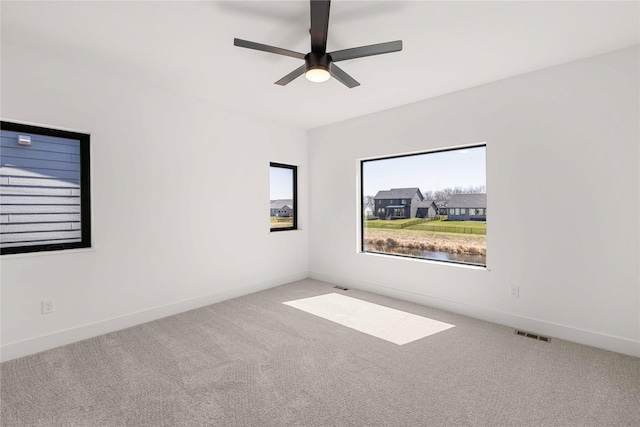 carpeted empty room featuring visible vents, baseboards, and ceiling fan